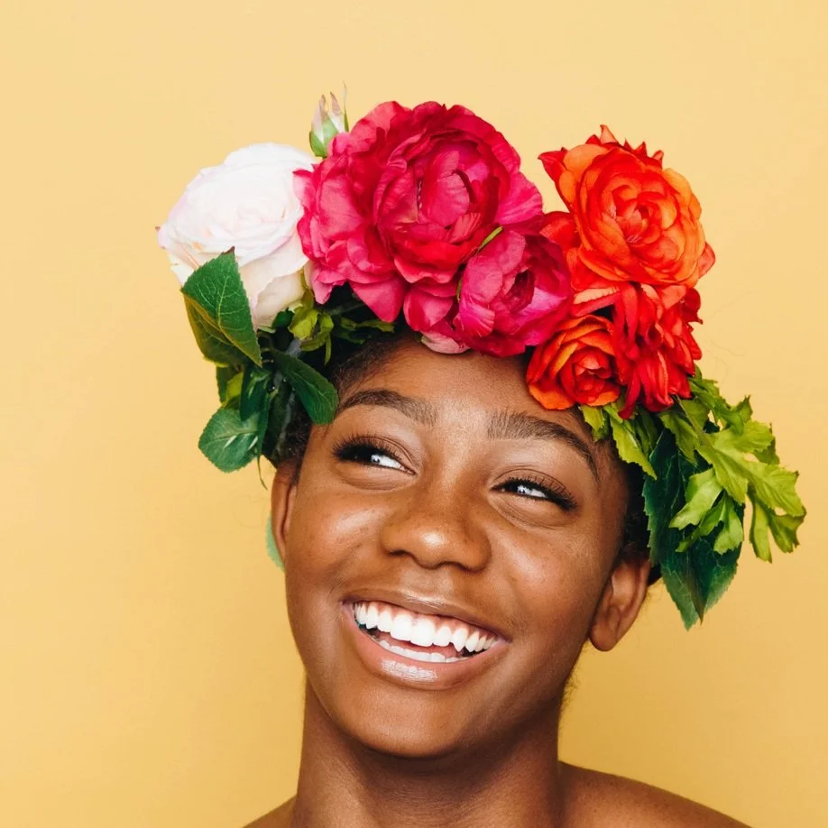 Black woman with flower crown in front of yellow background