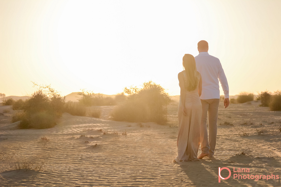 Dubai Maternity Photography portrait of expectant couple walking into the horizon as the sun sets down