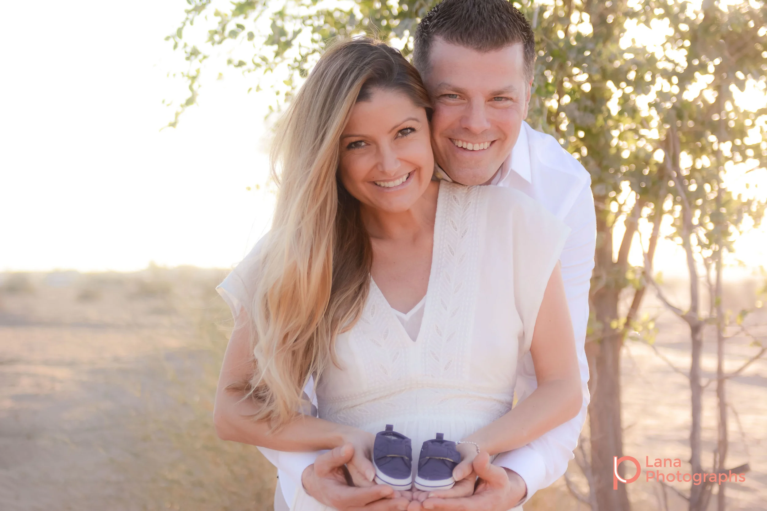 Dubai Maternity Photography portrait of expectant couple smiling while holding their future son's shoes in their hands