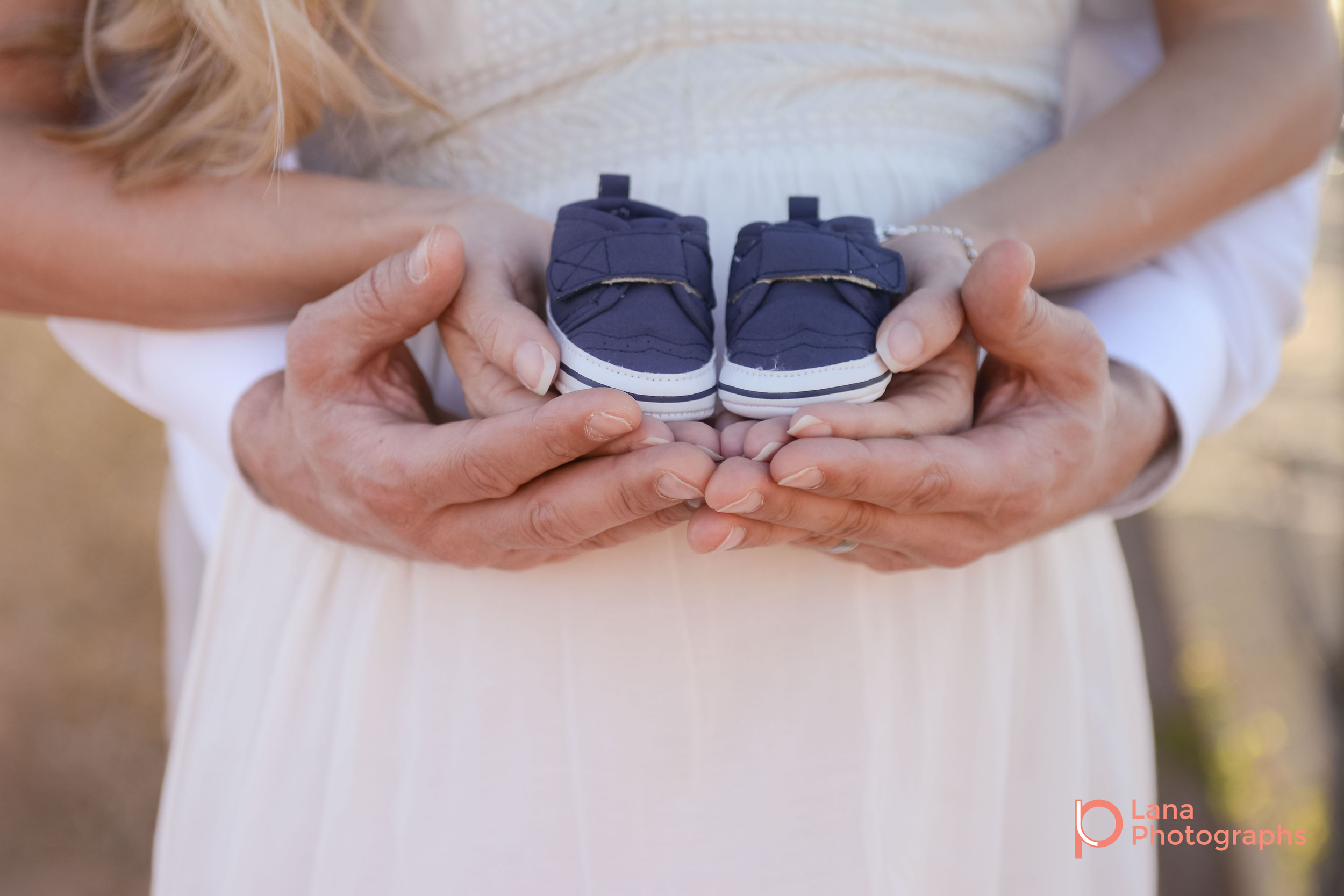 Dubai Maternity Photography portrait of expectant couple posing while holding their future son's shoes in their hands