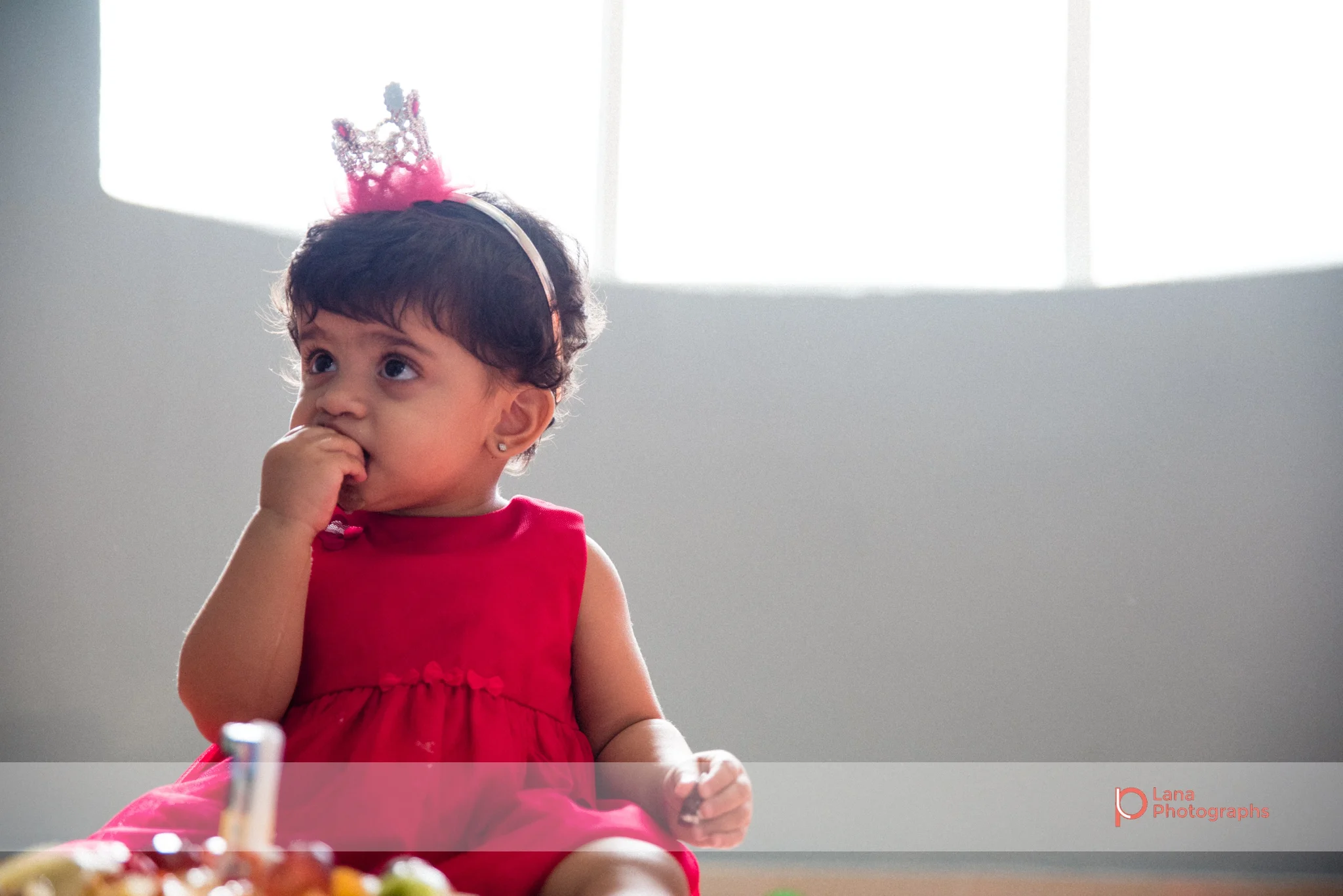 playing near a table showing a reflection of her birthday balloons little girl eating her birthday cake