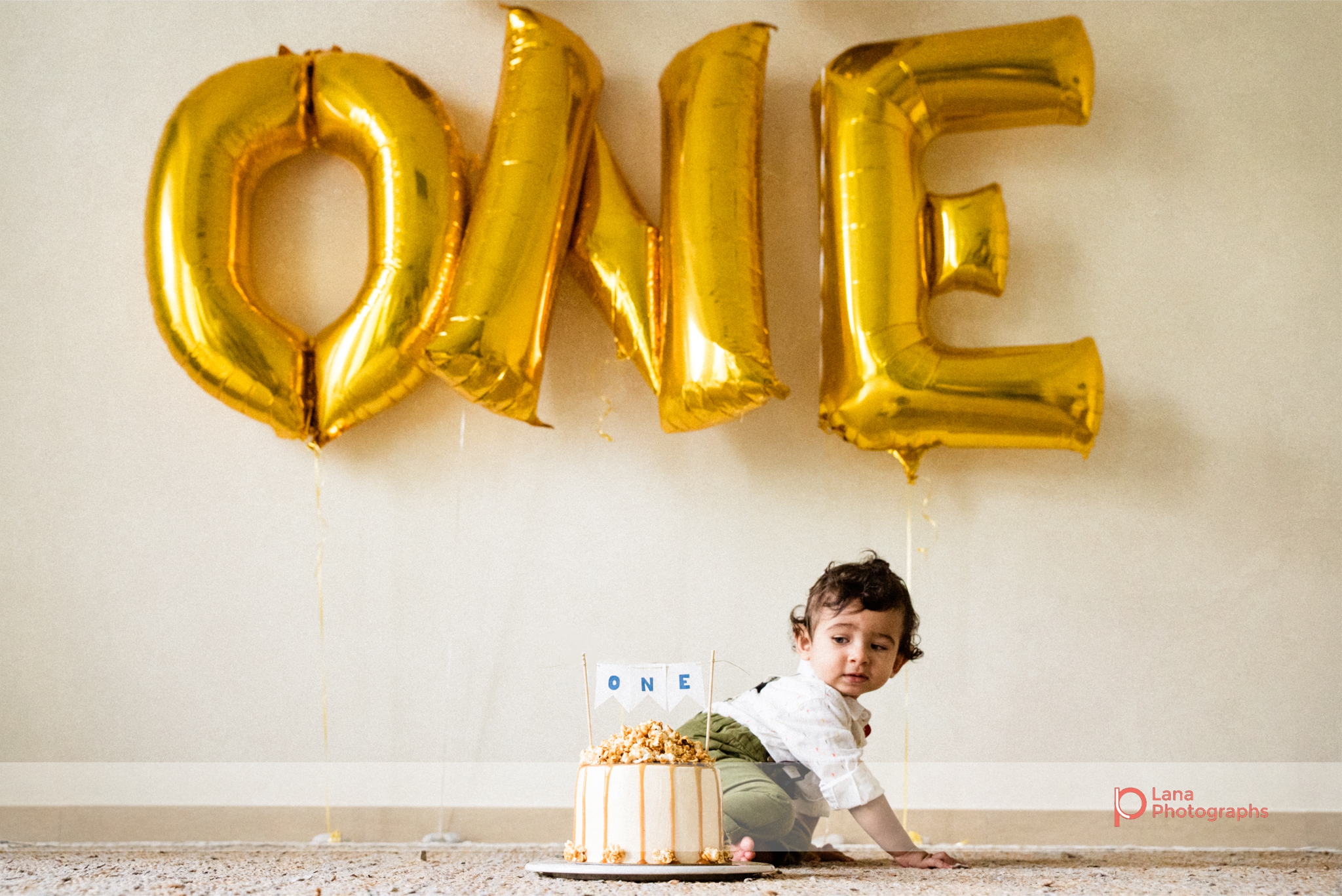 Cake Smash Dubai Baby poses with birthday cake and balloons
