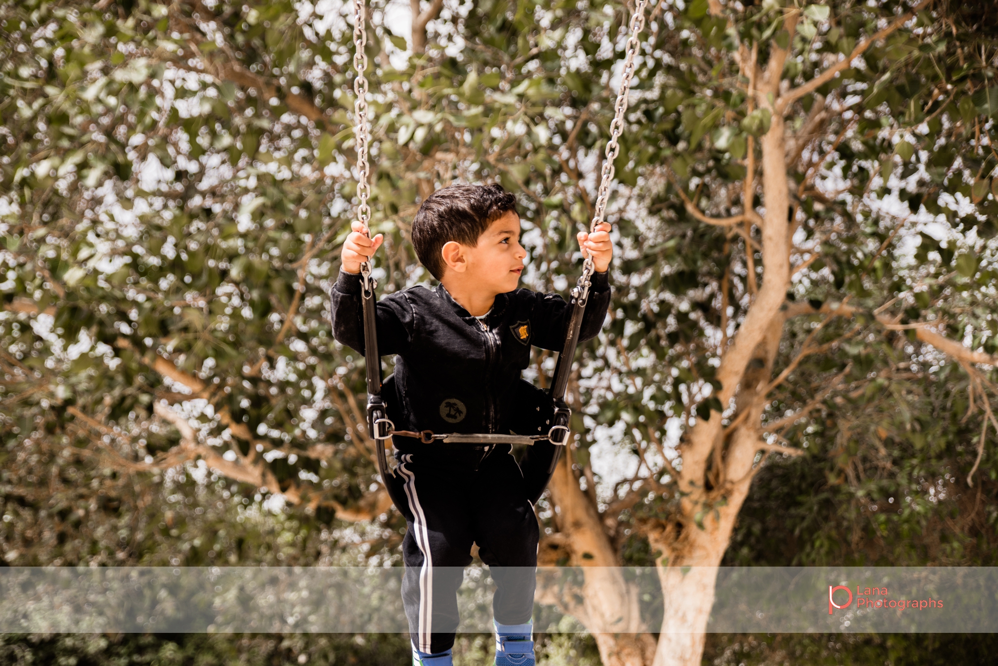 Dubai Family Photographer little boy swinging on the swings in Umm suqeim park Dubai