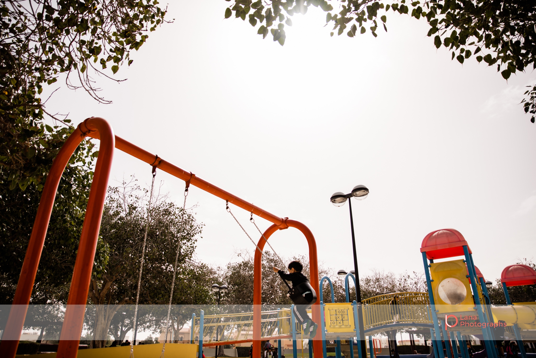 Dubai Family Photographer wide angle shot of a little boy swinging on the swings in Umm suqeim park Dubai