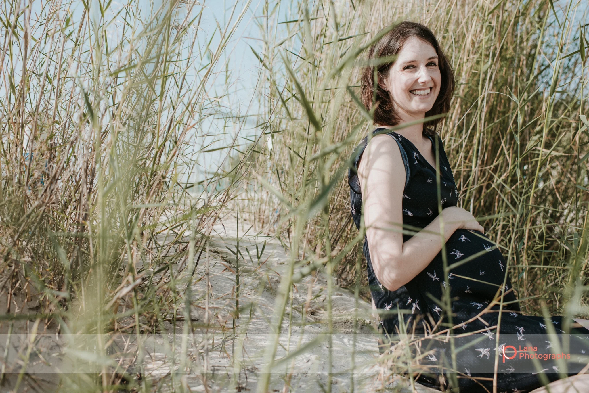 Lana Photographs Maternity Photography Dubai Professional Maternity Photographer pregnant woman sitting in shrub by the beach