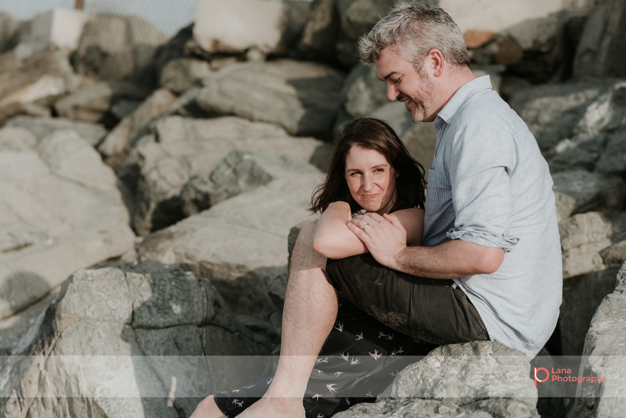 Lana Photographs Maternity Photography Dubai Professional Maternity Photographer husband and wife sitting on the rocks by the beach