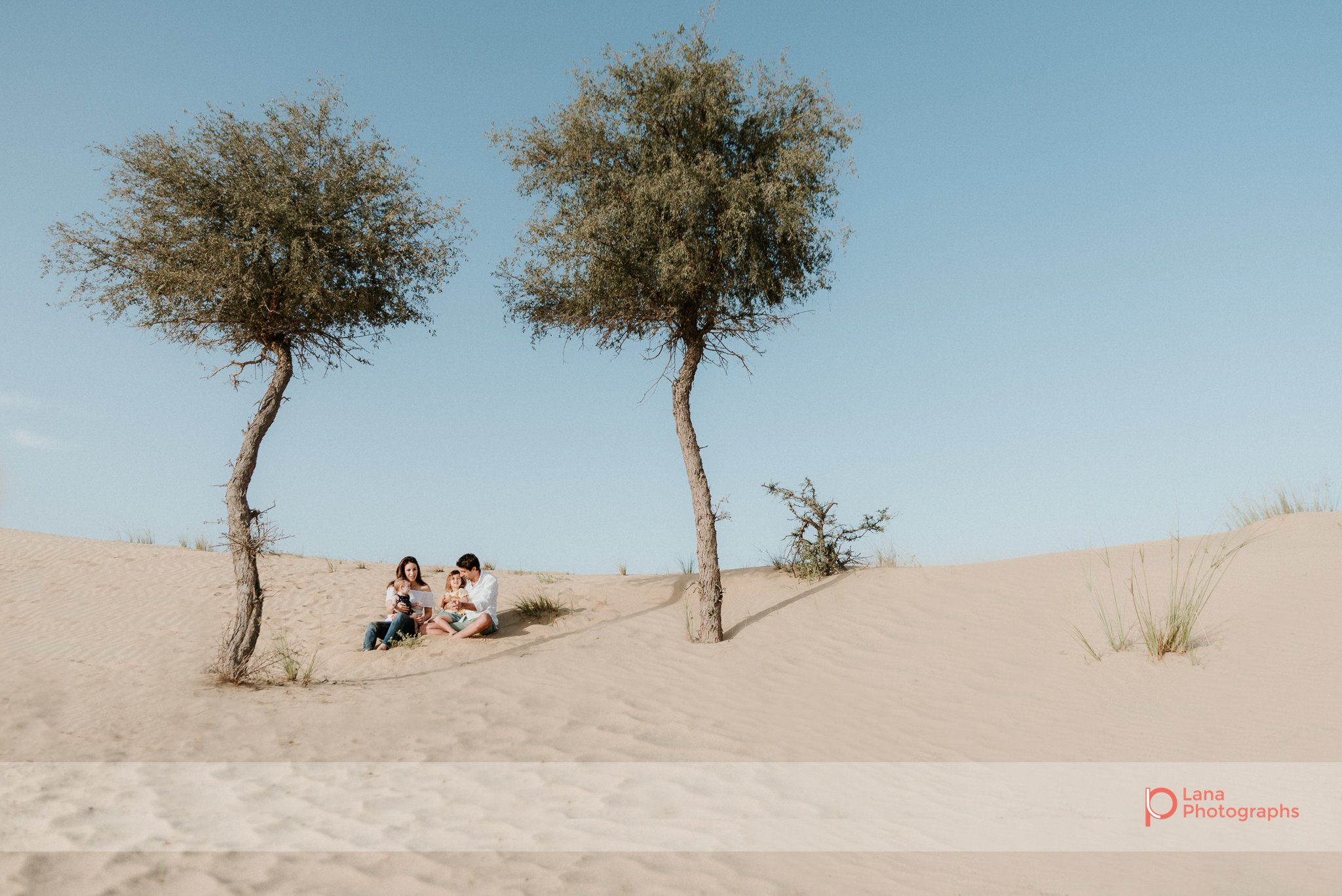  Lana Photographs Family Photographer Dubai Top Family Photographers family portrait sitting between trees in the desert