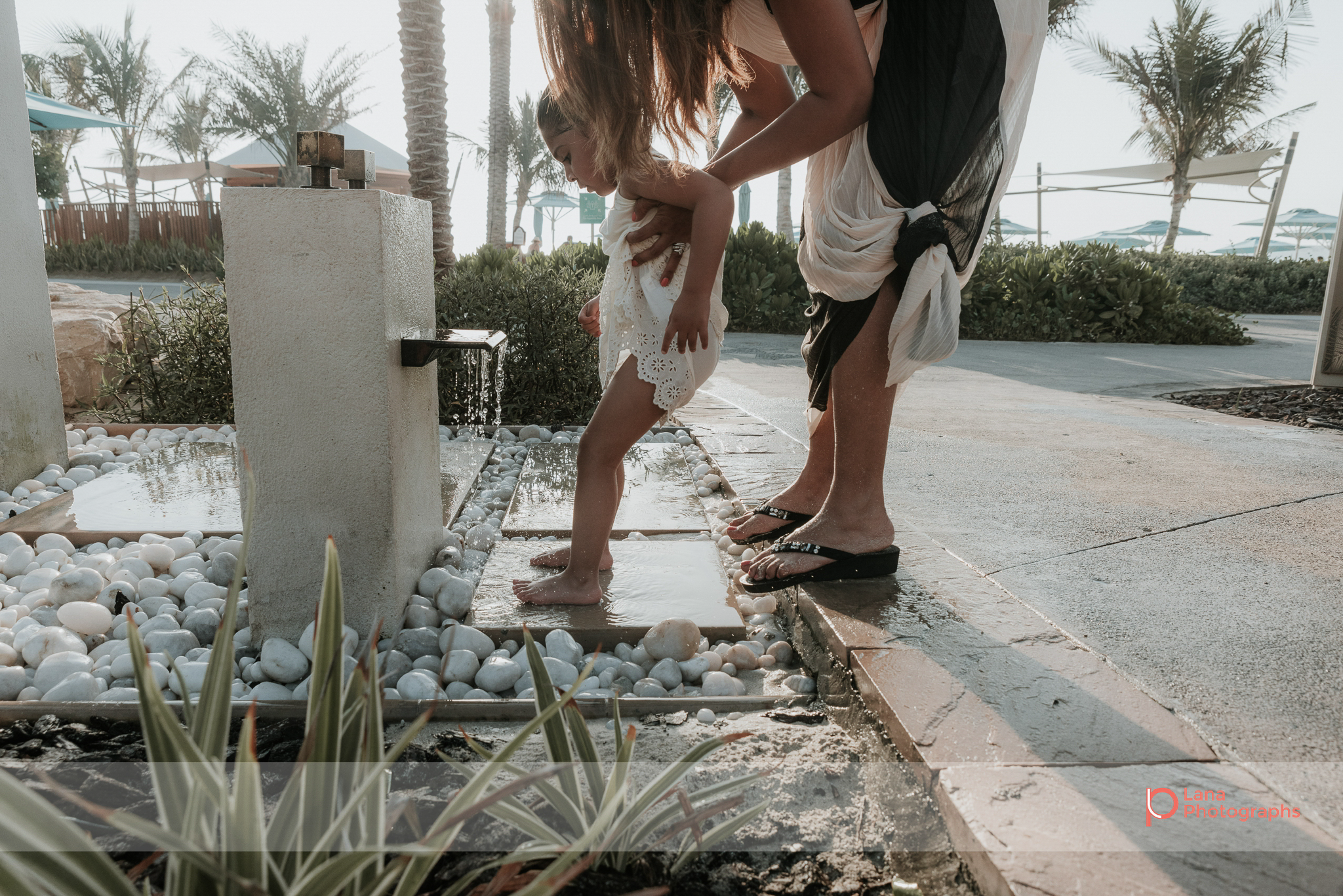  Lana Photographs Dubai Family Photography beach photoshoot mother washes sand off daughter's feet 