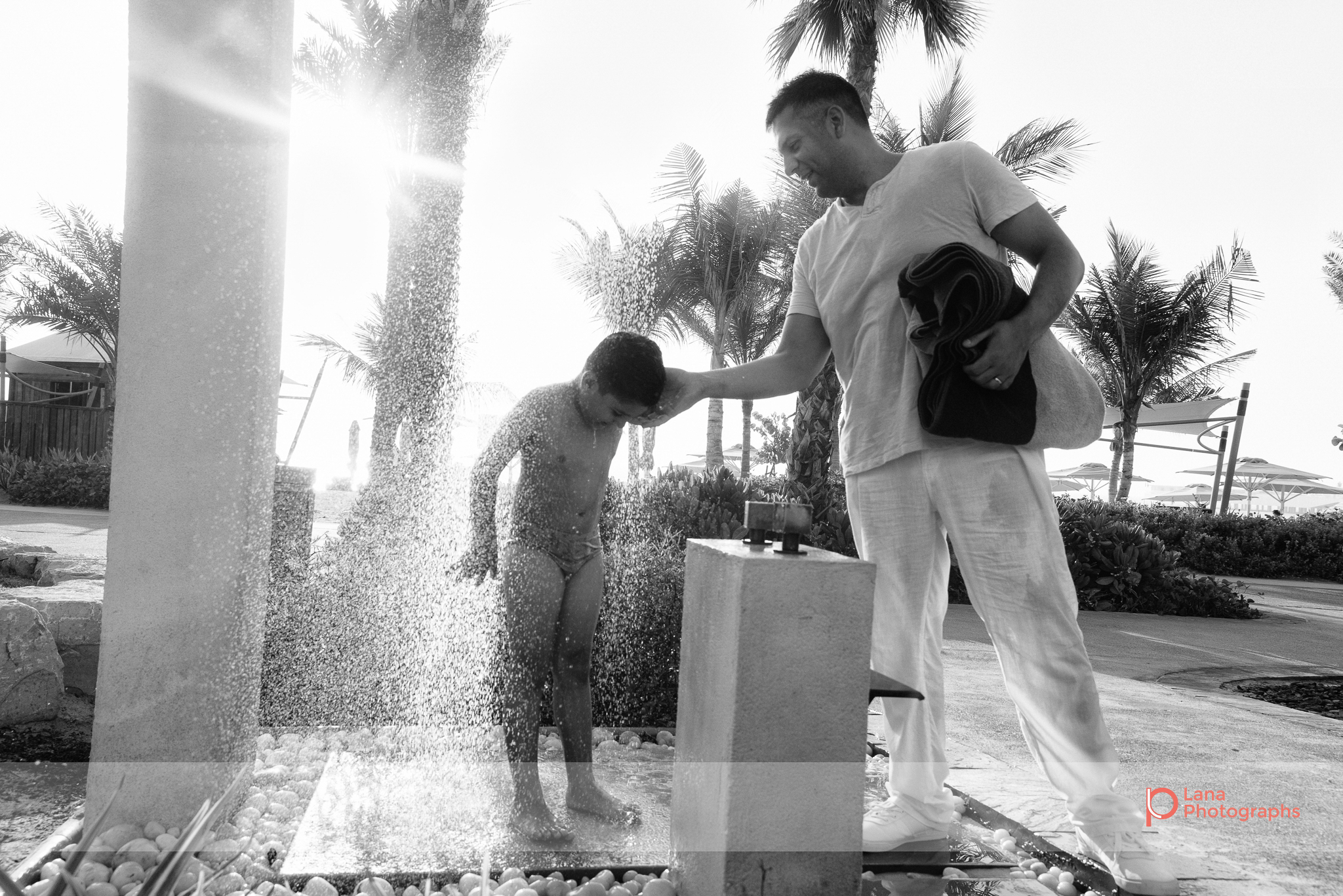  Lana Photographs Dubai Family Photography beach photoshoot father washes sand off son 