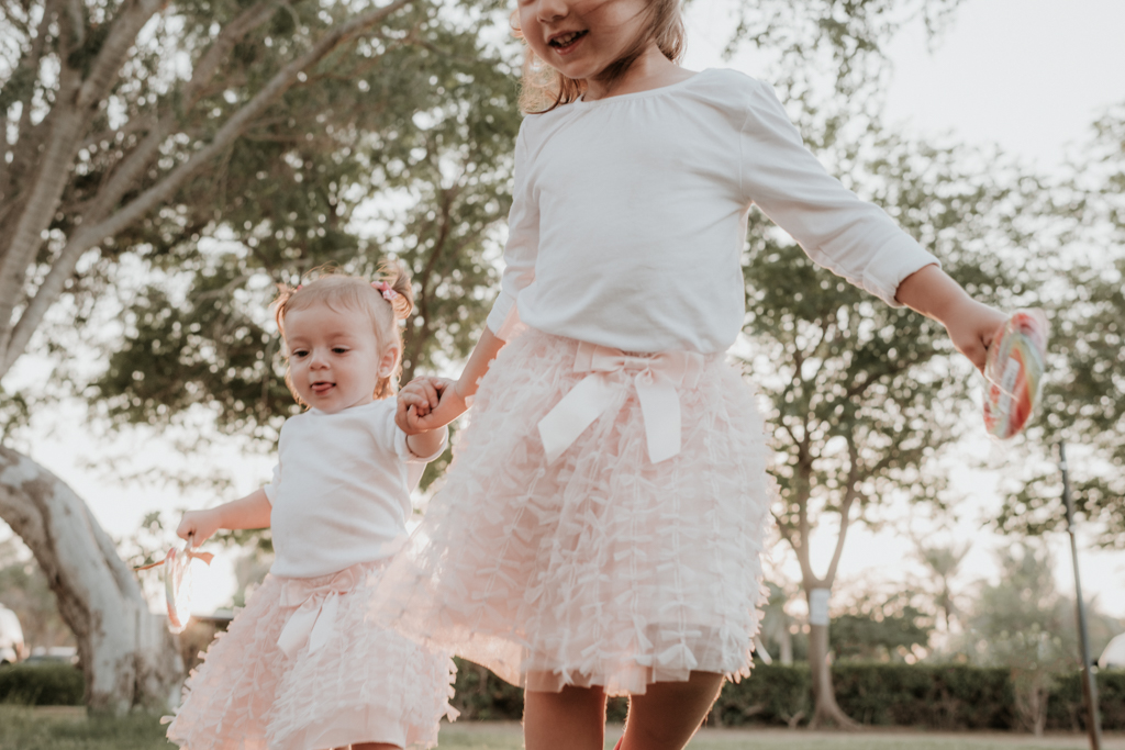 Lana Photographs Dubai Family Photographer two girls in pink tutus running holding hands