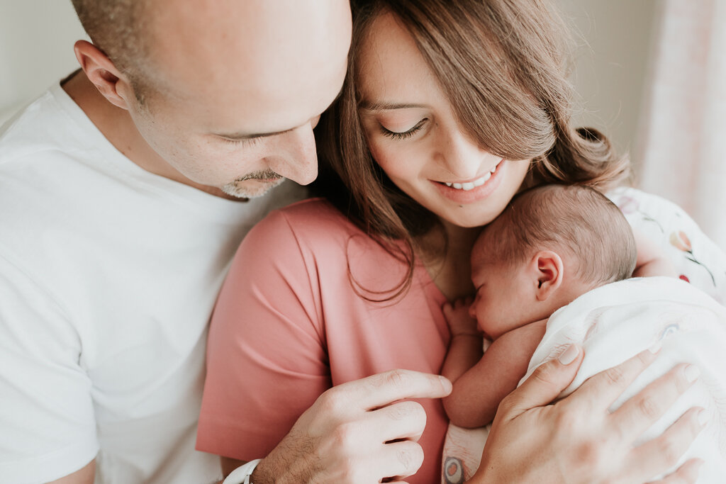 mother and father wearing neutral colors holding their newborn baby fondly lana-photographs-chicago-newborn-photographer