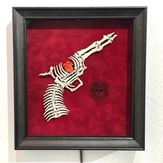 Bone Gun Emek removable, handpainted pearlesscent resin, embedded magnets, with glowing bullet hole, red velvet, hinged frame 15.5 x 14 x 3.75 inches Edition of 25 $1400 Click HERE to view video of gun being removed