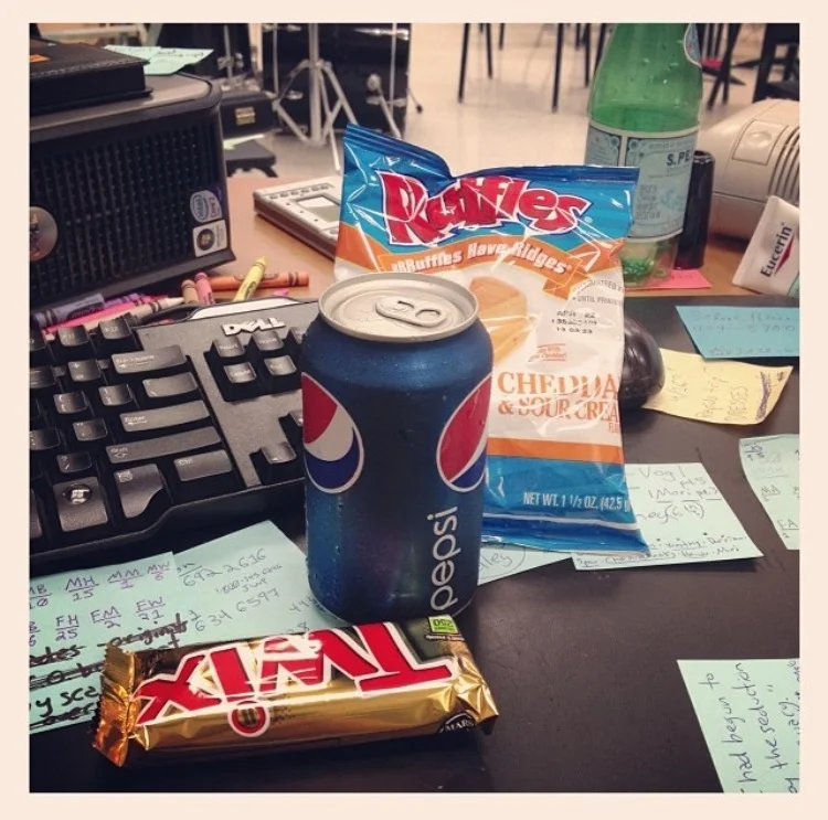 Image description: my desk, lots of post-it notes, and my lunch for the day -- a Twix bar, can of Pepsi, and a bag of Sour Cream & Cheddar Ruffles chips.