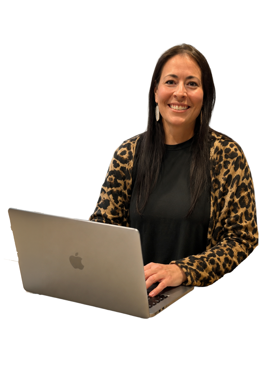 A woman smiling while sitting at a table with a silver Apple MacBook laptop