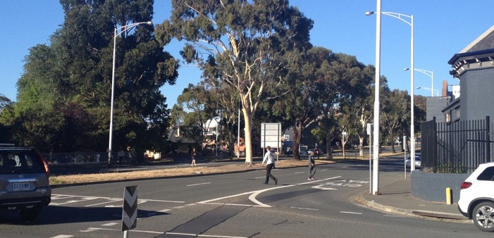 Early morning and three Pedestrians cross Burnett Street directly above its Underpass. 