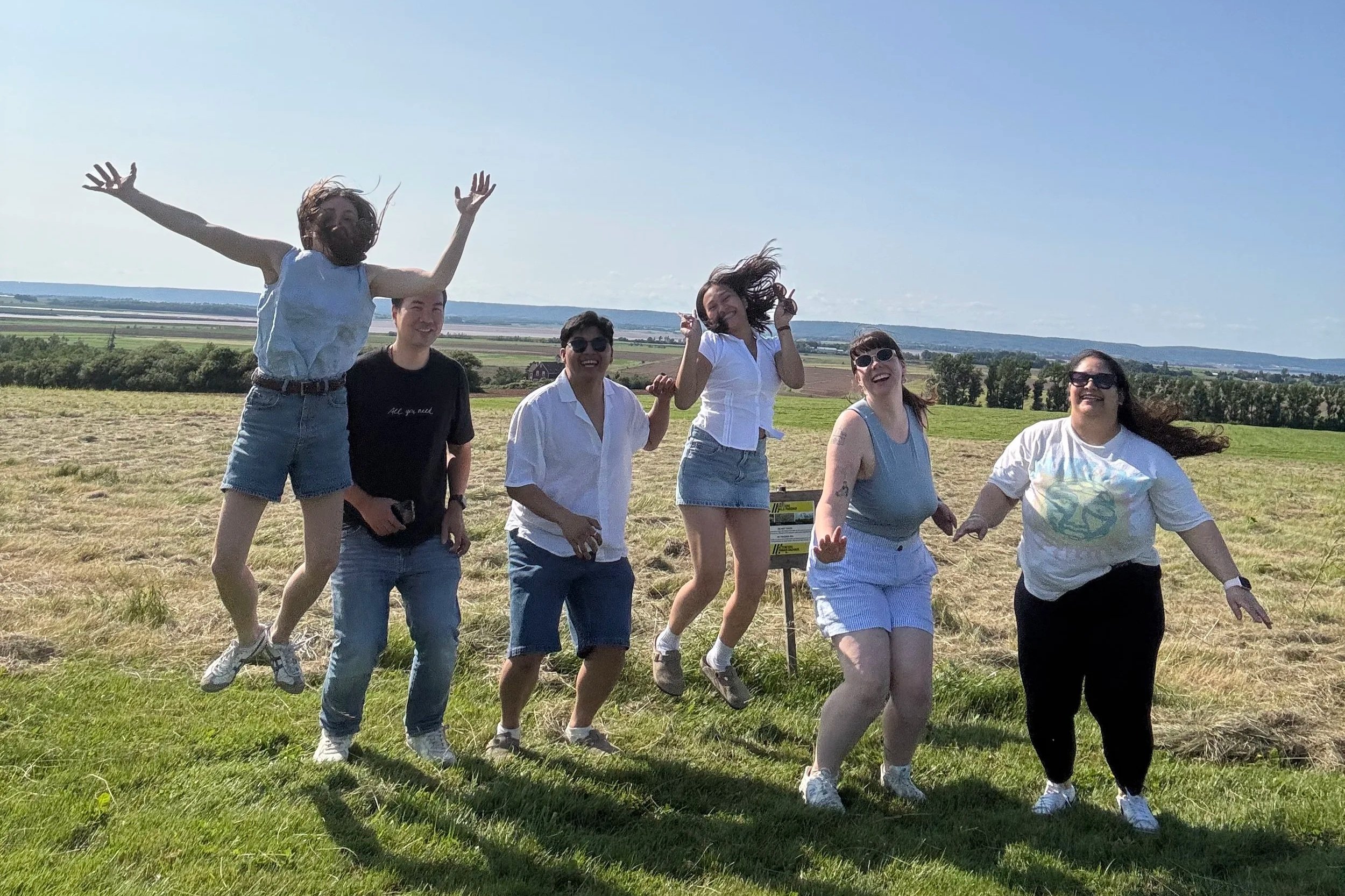 Hanna and Sam mid jump with group tour in a field.