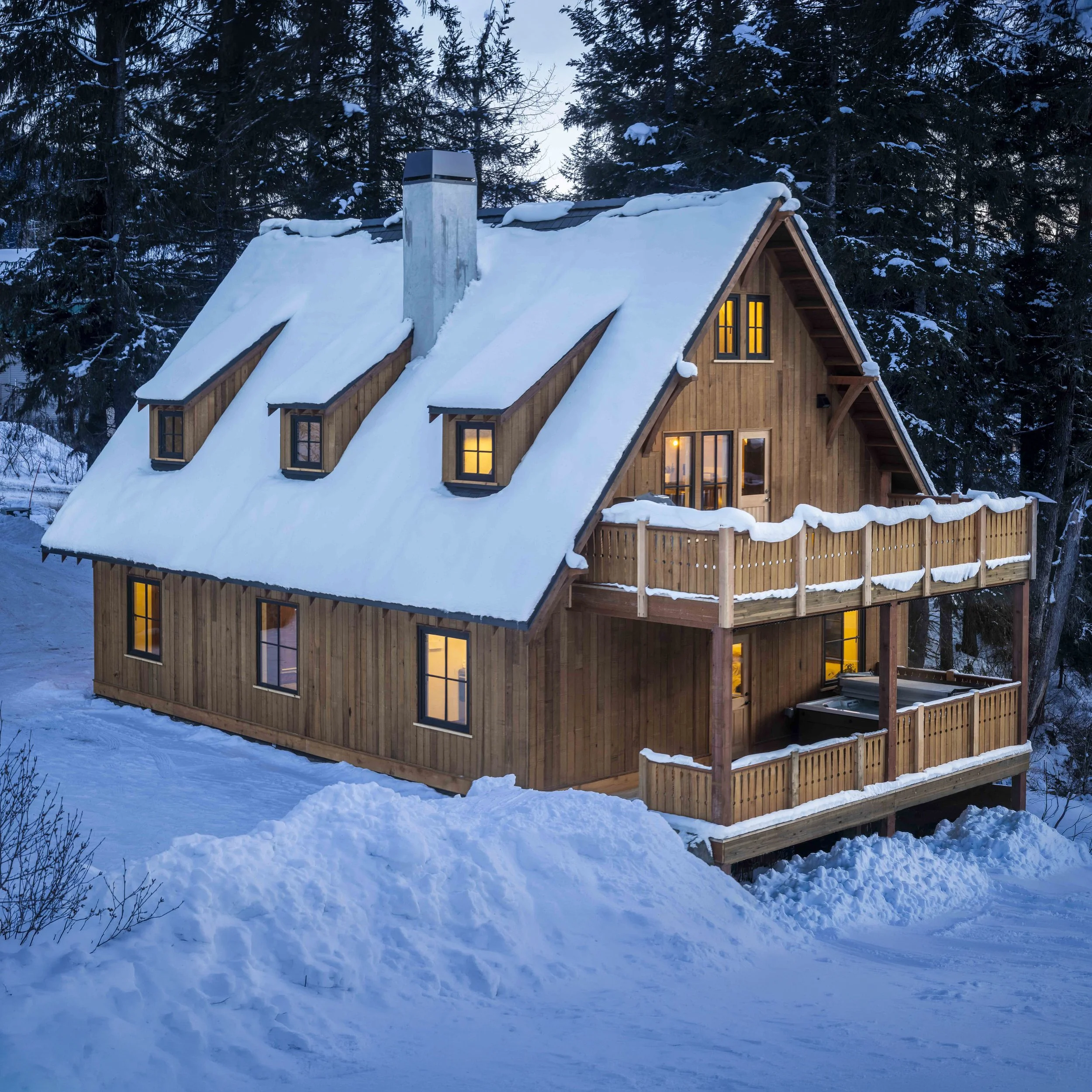 WillowRidge Construction's take on a Bavarian ski cottage on a cool cool winter evening, snow covering the house and deck during sunset.