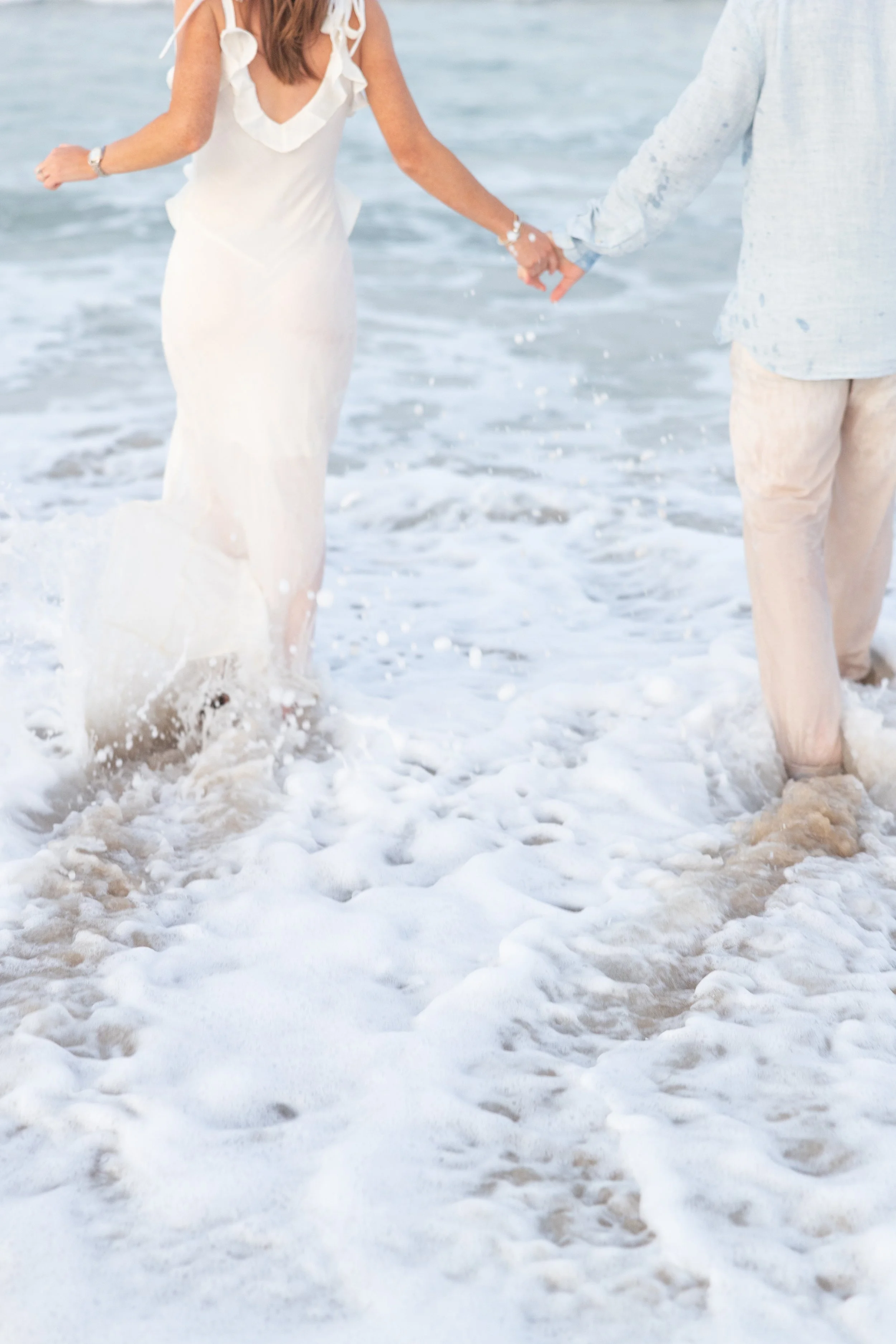 cape cod engagement session couple holding hands running into ocean surf coast guard beach eastham ma