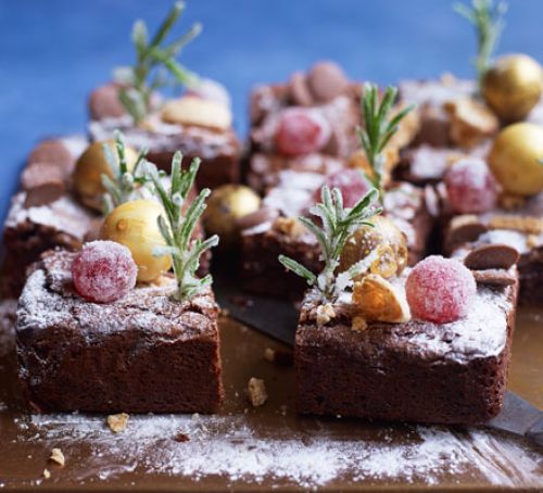 Ingeredients: 200g unsalted butter cut into cubes, plus extra for greasing, 100g dark chocolate, chopped, 100g milk chocolate, chopped, 3 large eggs, 300g golden caster sugar, 100g plain flour, 50g cocoa powder, ½ tsp mixed spice For decorating: rosemary, glacé cherries, 1 egg white, caster sugar, 4 amaretti biscuits, crushed, 9 chocolate truffles, 1-2 tsp icing sugar for dusting, chocolate button, edible silver balls