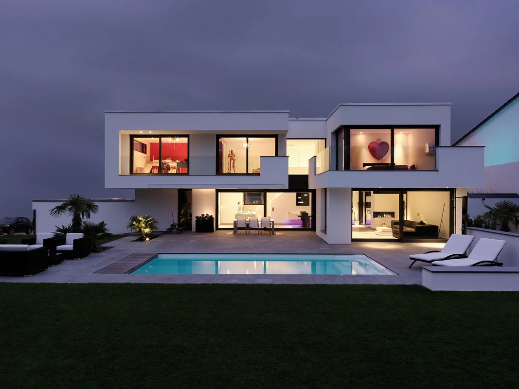 EPPINGEN, GERMANY - a Caribbean atmosphere with an outdoor pool and palm trees in the garden. The two-storey Villa Belice is situated in a quiet neighbourhood bordering a nature reserve. The building is characterised by recesses and projections in the façade and dramatic contrasts in colours and materials. 