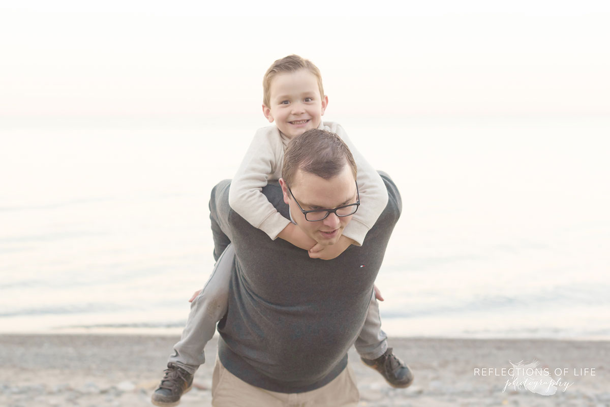 little boy playing with dad on the sandy beach in southern ontario canada
