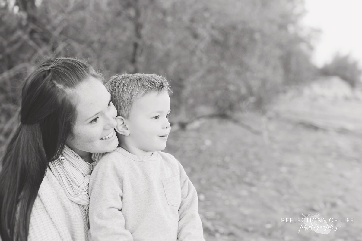 little boy sitting with mom on the sandy beach in southern ontario canada