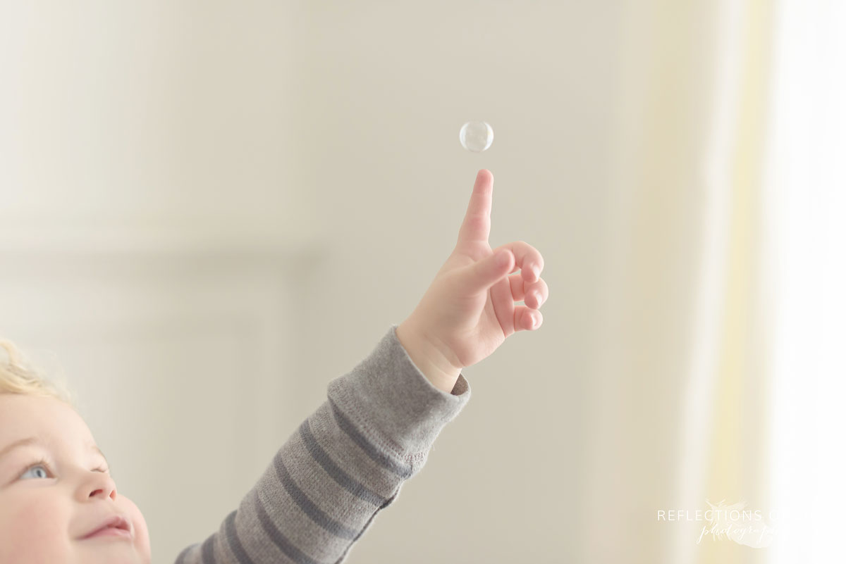Baby boy playing with bubbles in the natural light studio Niagara Falls Ontario