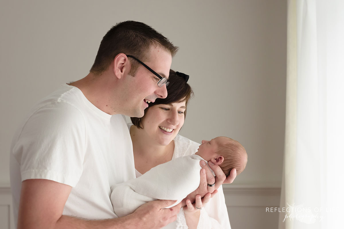 015 Mom and dad look down at brand new baby Professional Newborn Photography