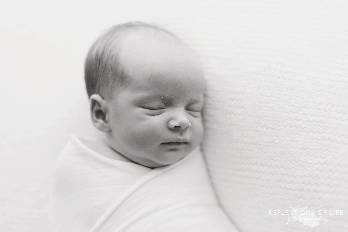 black and white portrait of newborn baby swaddles in white 001