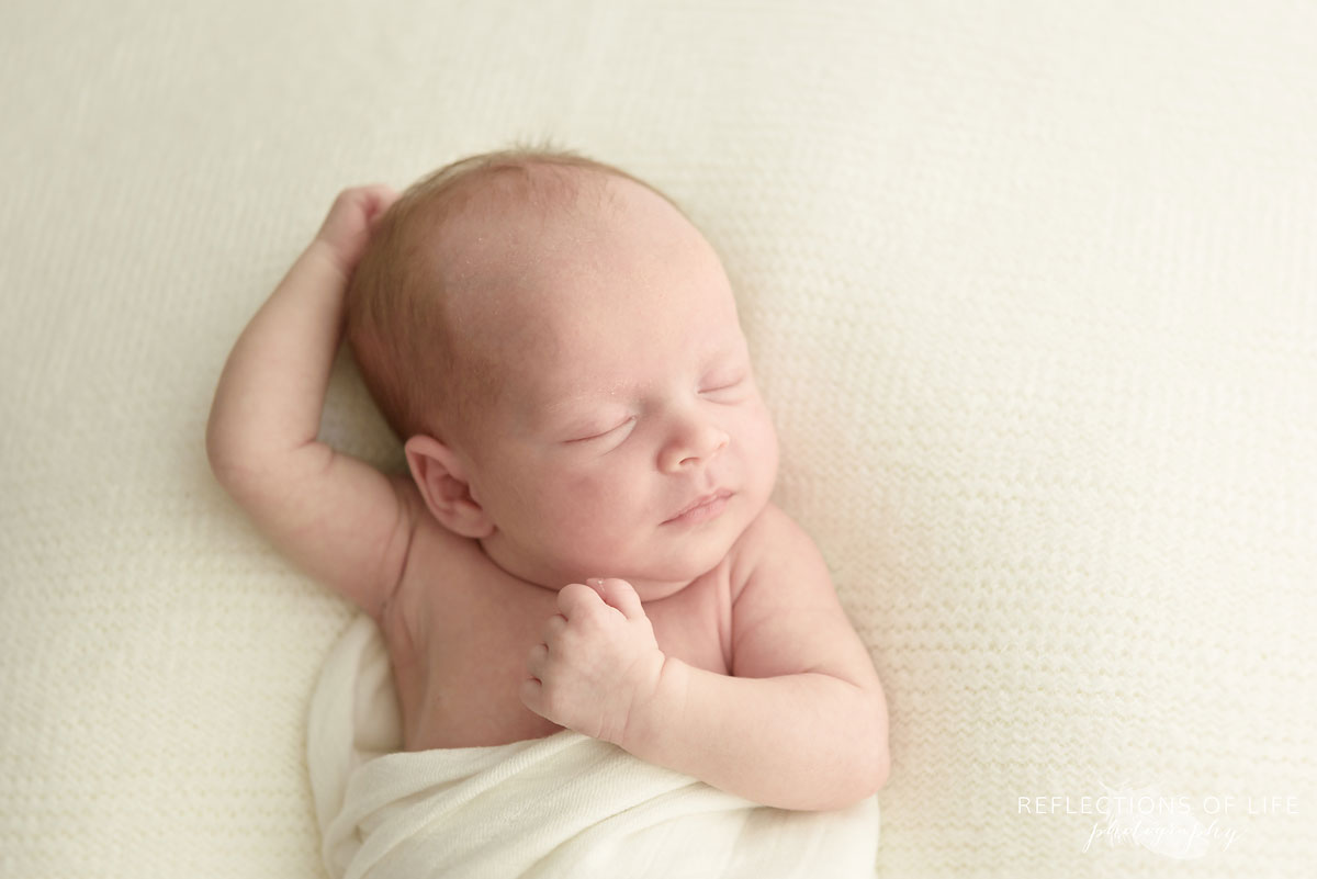 newborn baby with arms by face and head 007