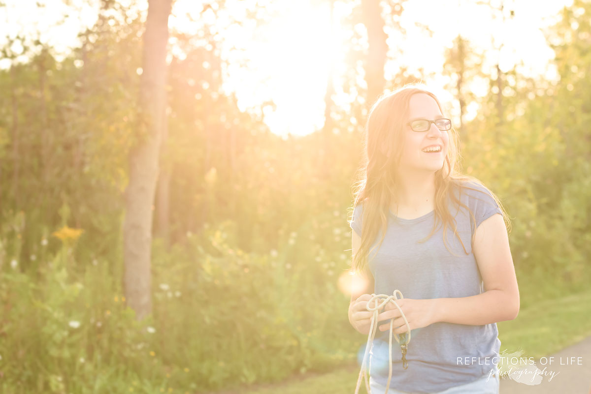 Candid image of girl walking down a path with sun shining though behind her