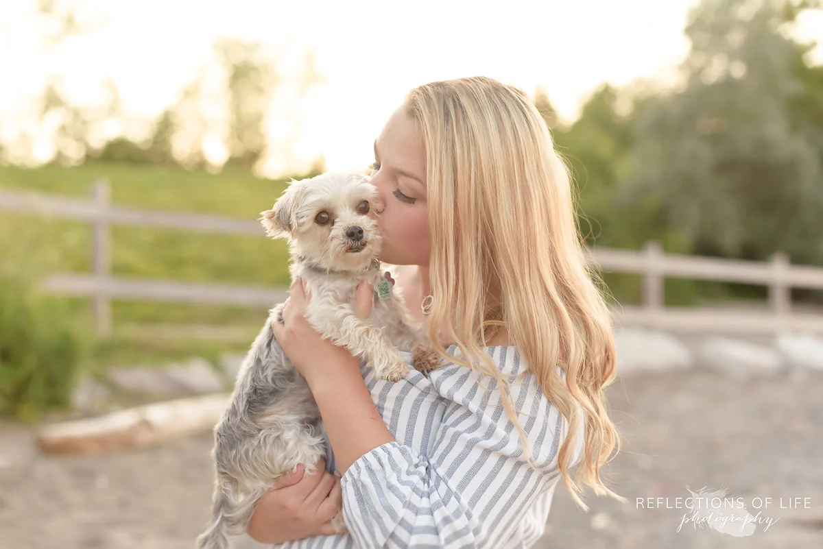 Pretty girl kissing morkie dog on the beach near Lake Ontario