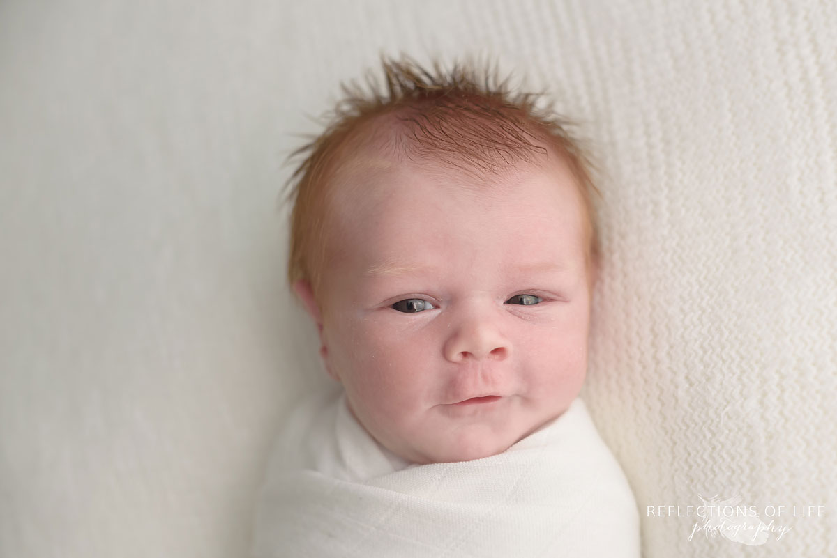 Redhead baby boy in white photo studio