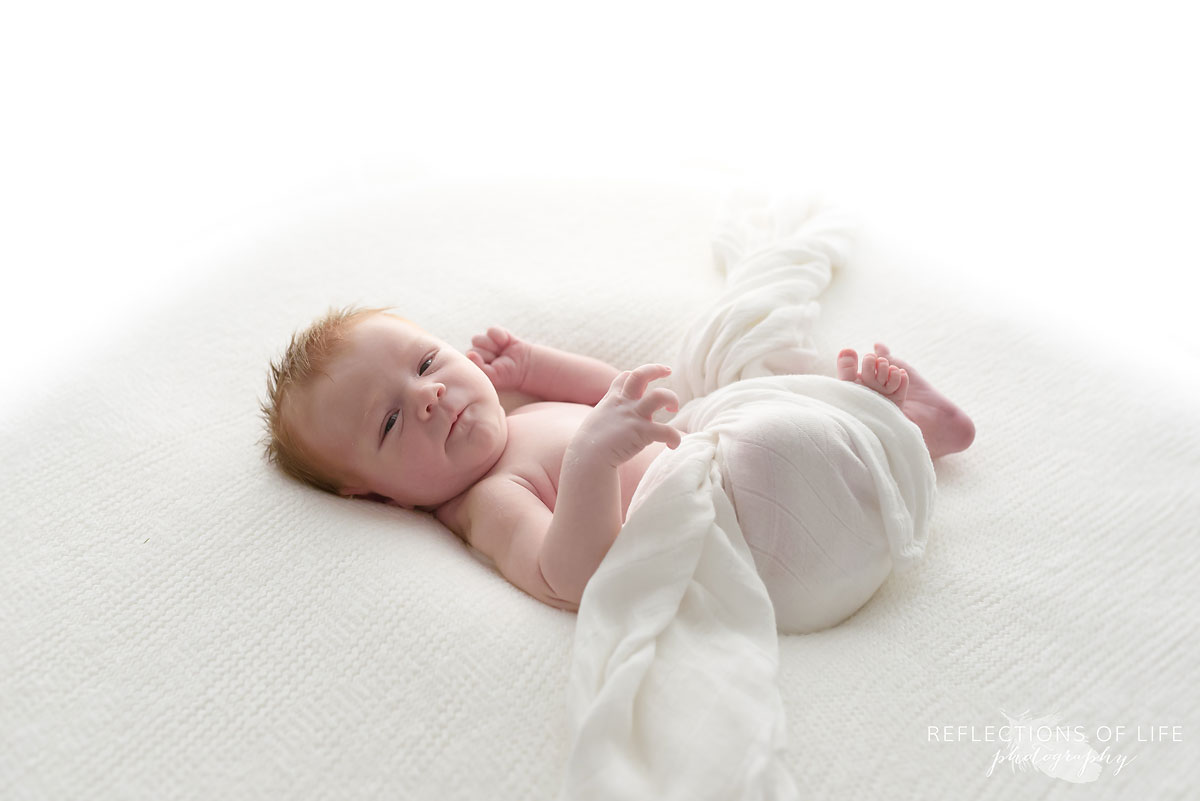 Professional newborn baby photo of boy looking at the camera