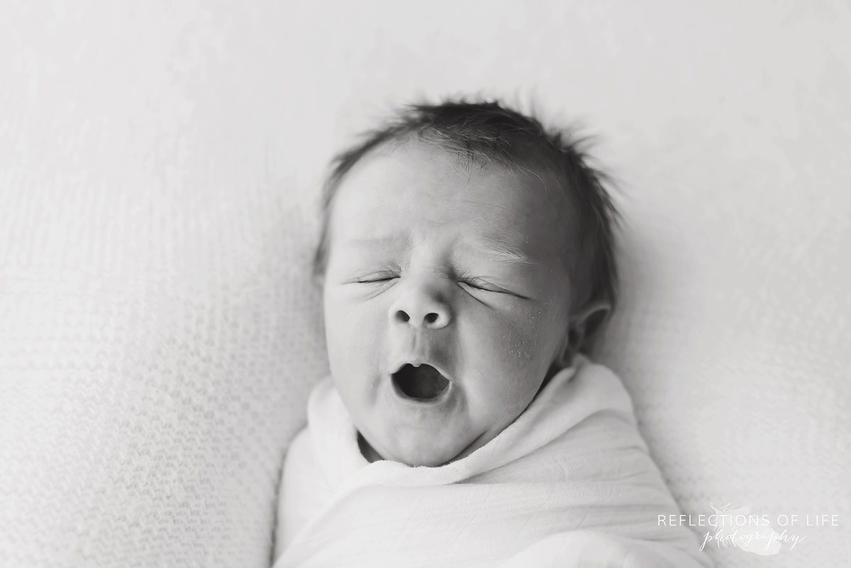 Black and white of newborn baby yawning