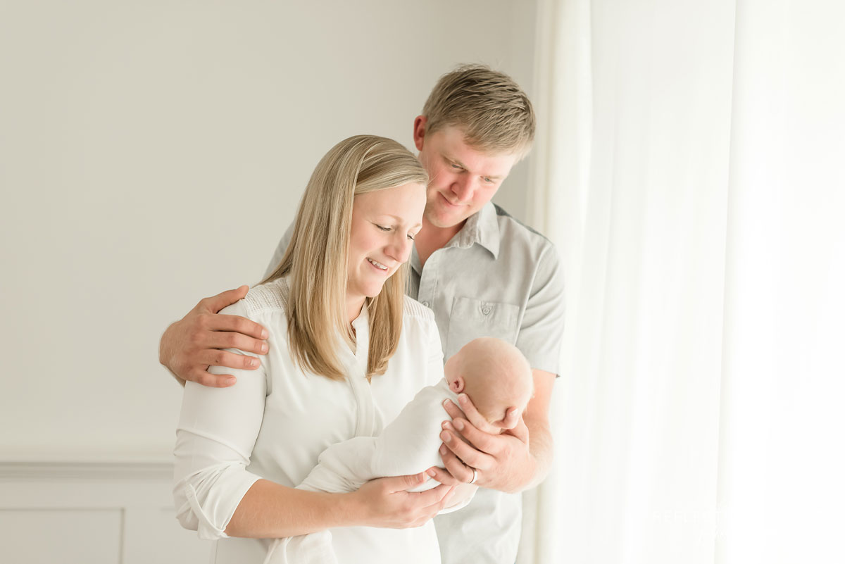 New parents holding newborn baby in white photo studio Grimsby