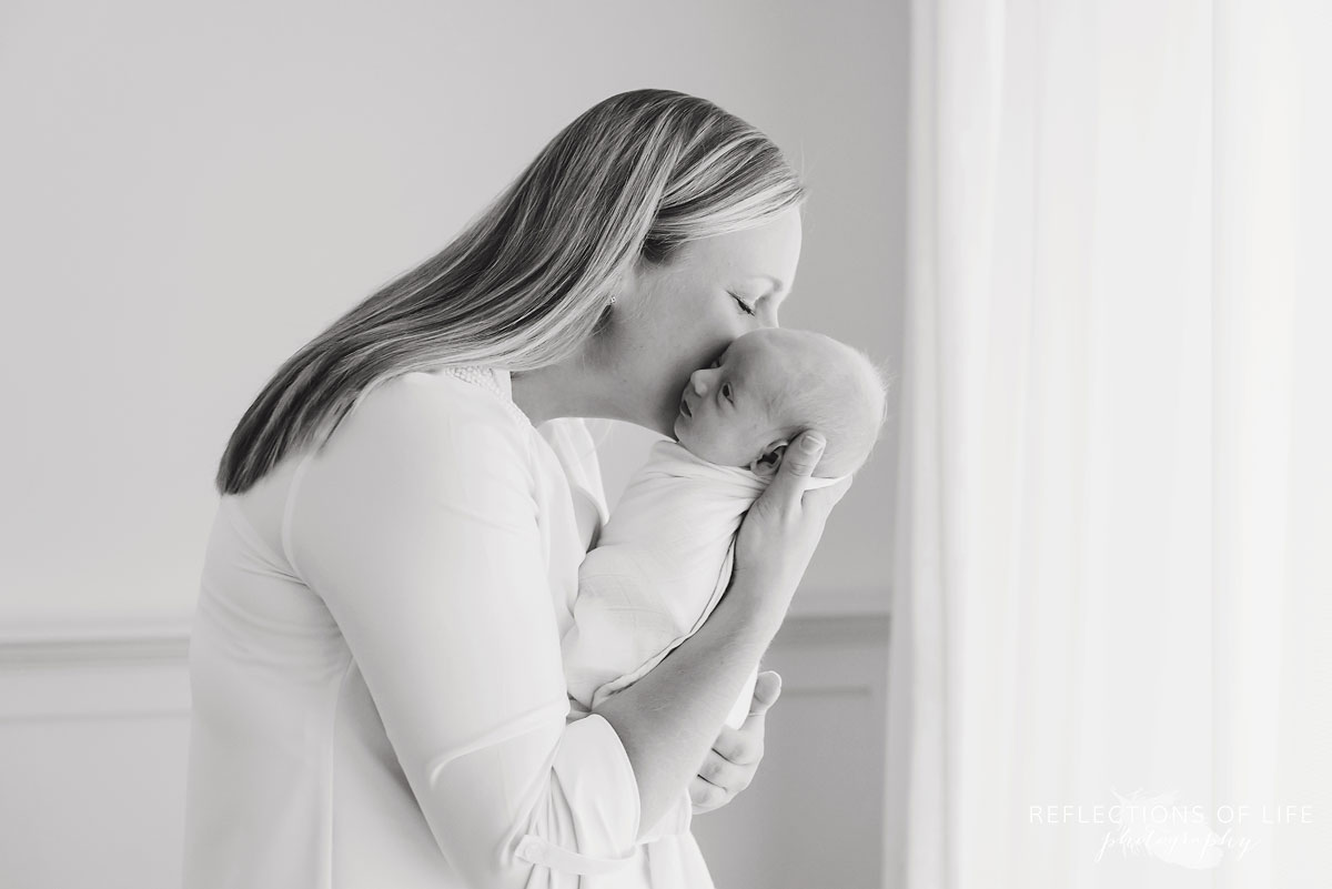 Mom whispering into ear of her newborn Niagara Newborn Photographer