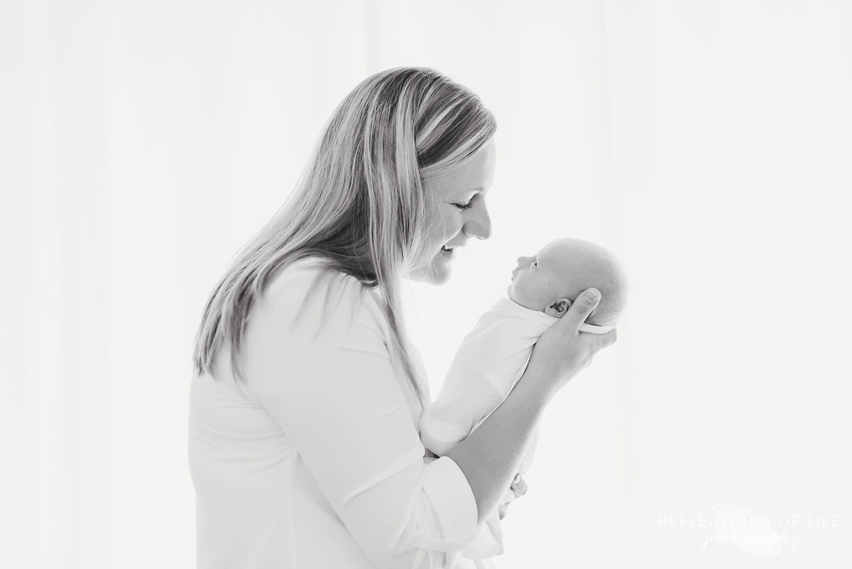 Black and white newborn and family image of mom looking down at baby