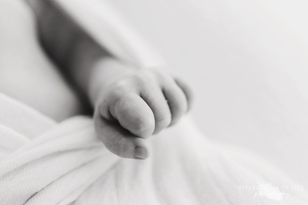 Adorable baby hand grasping muslin blanket