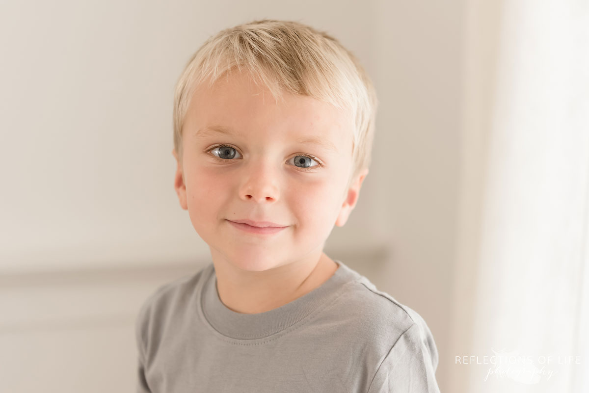 Colour portrait of little boy in gray shirt in natural light studio