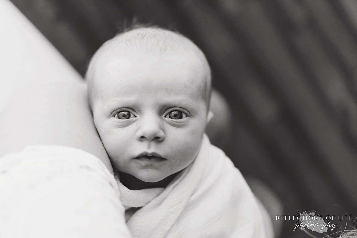 Newobrn baby girl looking up at mama with wide eyes