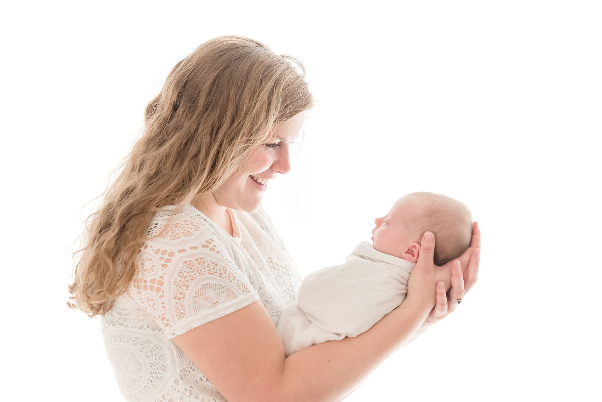 Proud mama holding her newborn baby backlit in studio