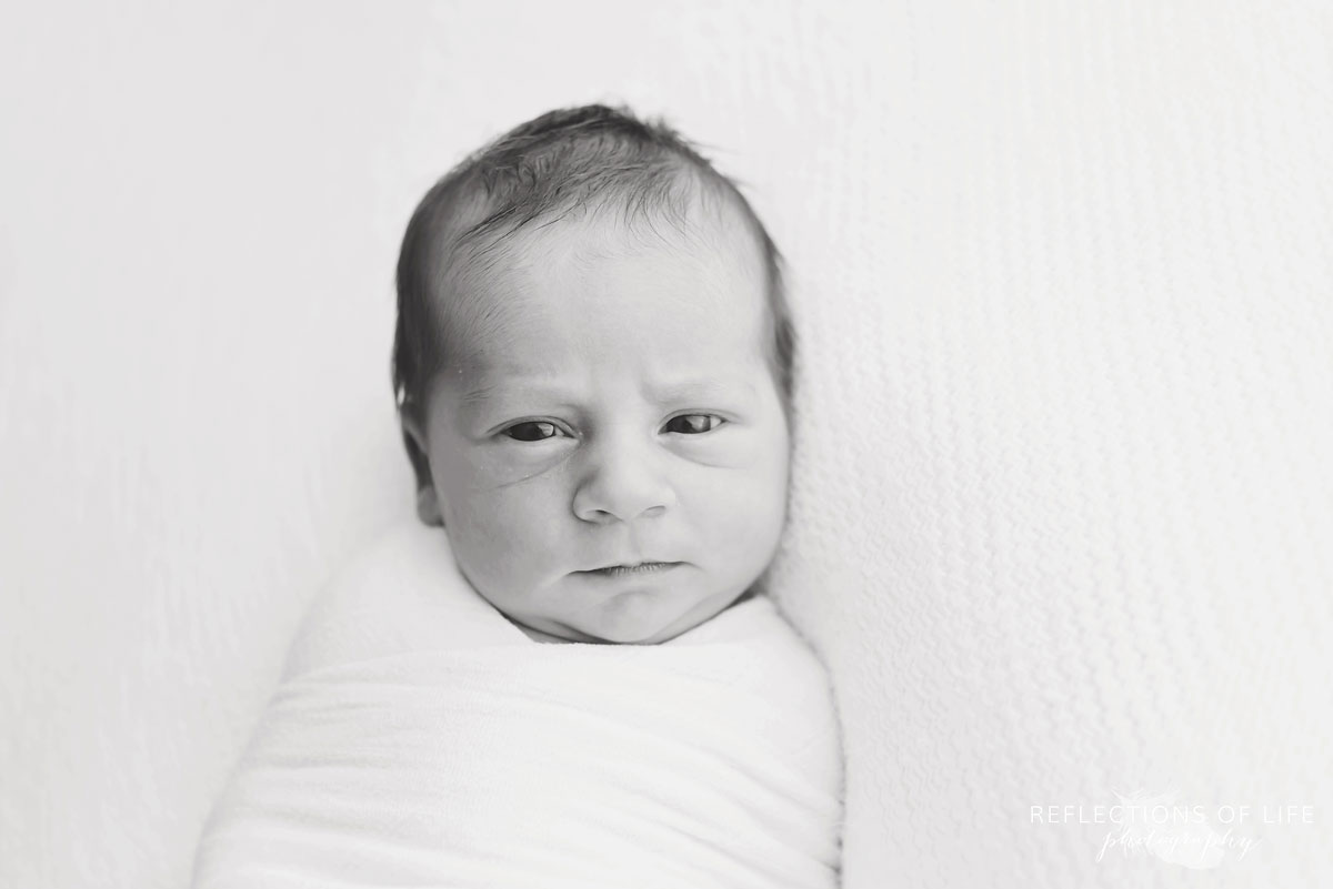 Black and white photo of newborn baby boy with eyes open