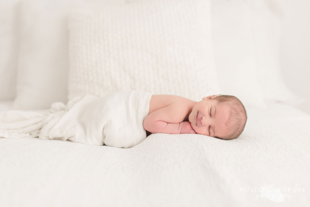 Colour photo of baby sleeping in white blanket