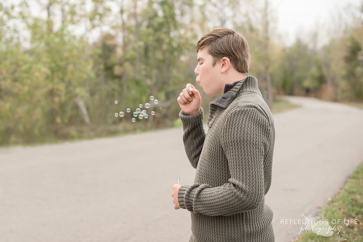 Teenage boy blowing bubbles on pathway in Grimsby Ontario.jpg