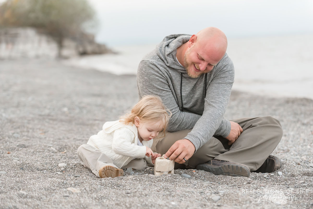 Father and son smiling as they build a tower out of rocks at the beach in Grimsby Ontario.jpg