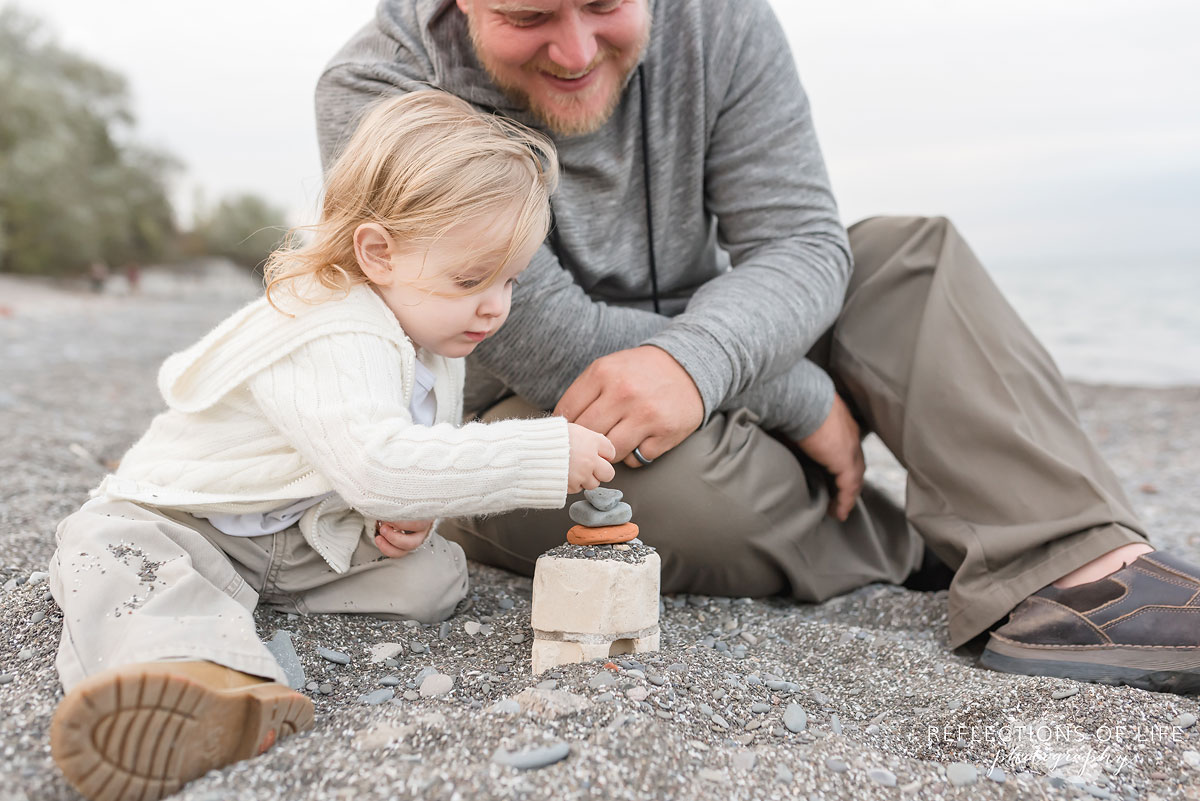 Father and toddler son happy to build a rock tower together in Niagara Ontario Canada.jpg