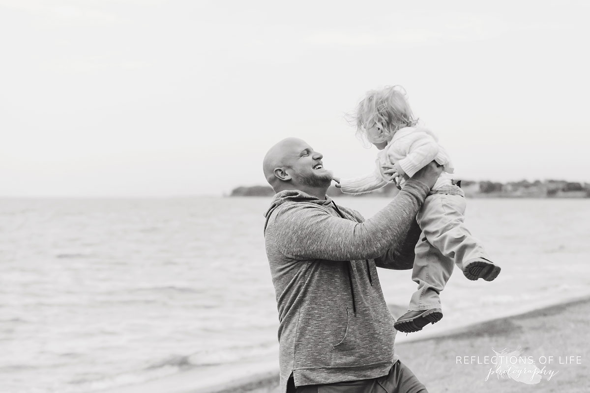 Black and white photo of father holding toddler son up in the air.jpg