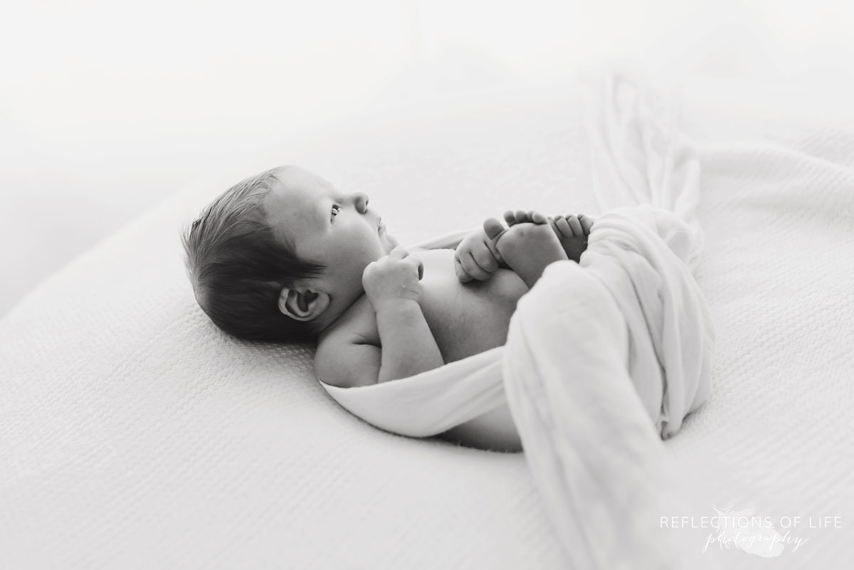 018 Black and white image of baby swaddled in white laying on white blanket.jpg