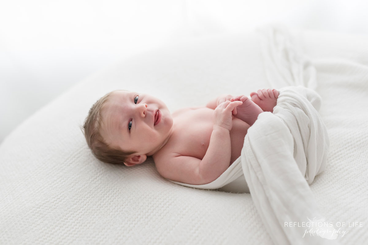 019 Colour image of baby smiling on white blanket.jpg